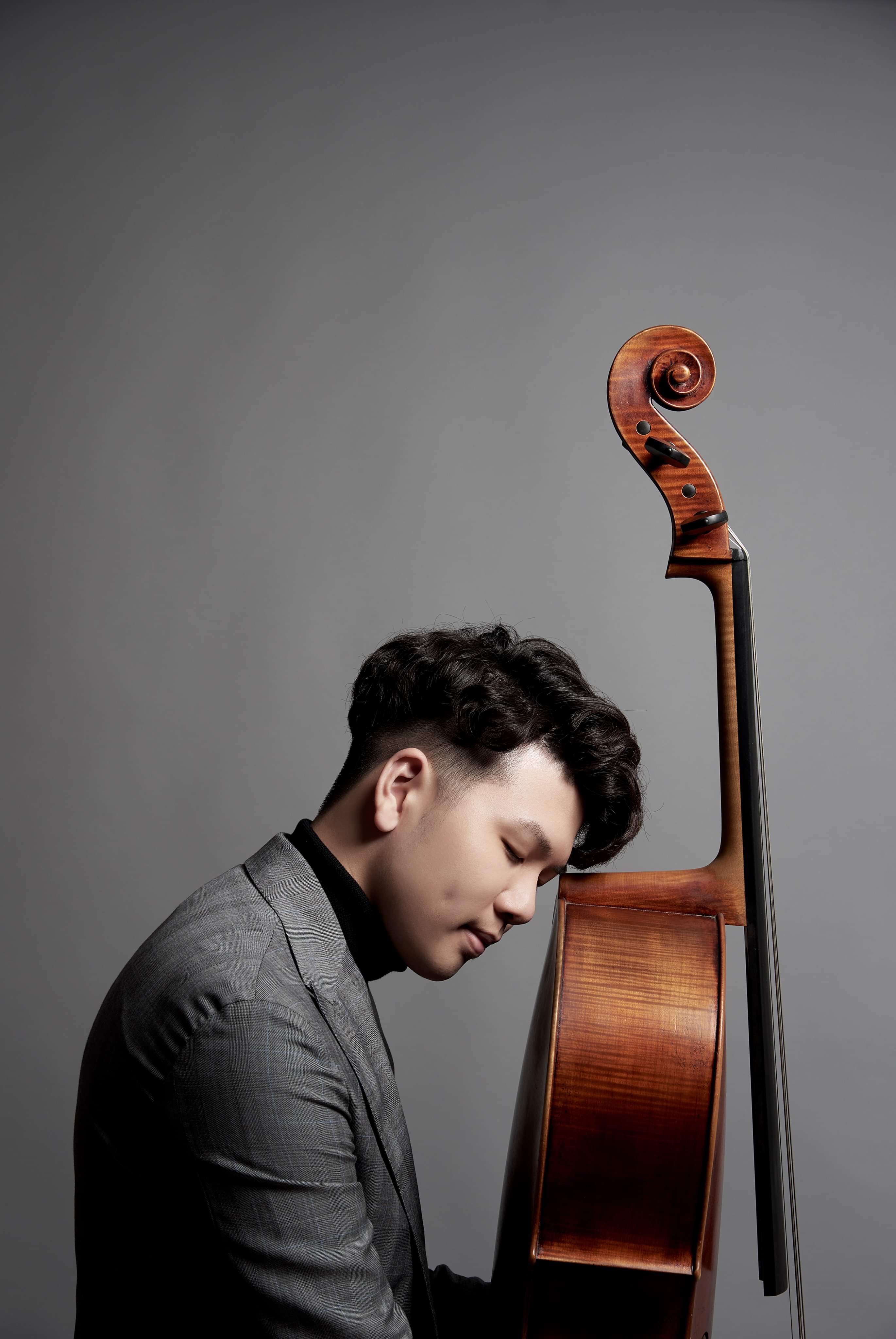 Vertical portrait of Yun Ho beside his cello